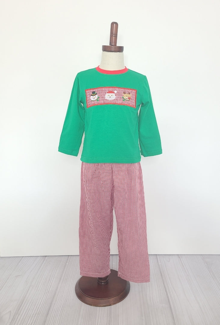 This Santa and Friends Smocked 2 Piece Pant Set is the perfect outfit for the holidays. The set includes red and white gingham pants and a long sleeve green shirt with smocking featuring an embroidered snowman, Santa and reindeer. Get your little one ready for the festive season with this festive and fun set.