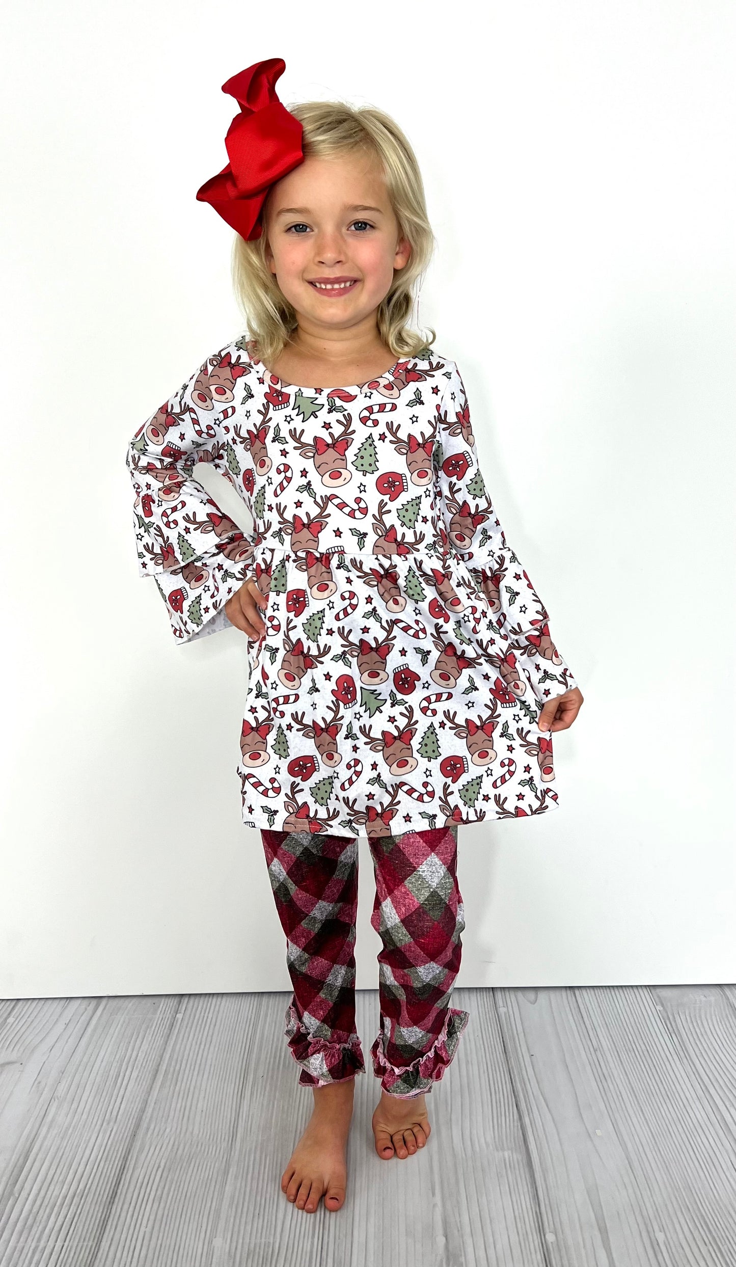 Stay festive & stylish in this fun Reindeer Plaid 2-Pc Girl's Pants Set! The oh-so-adorable bell-sleeve top has a Reindeer, candy cane, & tree print, while the ruffled ankle pant has a contrast print with a large check pattern. She'll love this special boutique outfit!