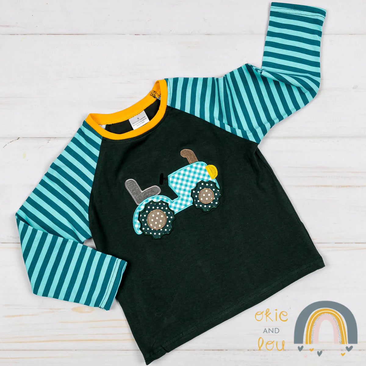 Gear up with this Terrific Tractor long sleeve Shirt. Featuring an adorable tractor applique and striped sleeve, this shirt is as cute as it is comfy! Loving the use of colors green, turquoise, yellow gold and black, you'll be stylishly revving around town in no time!