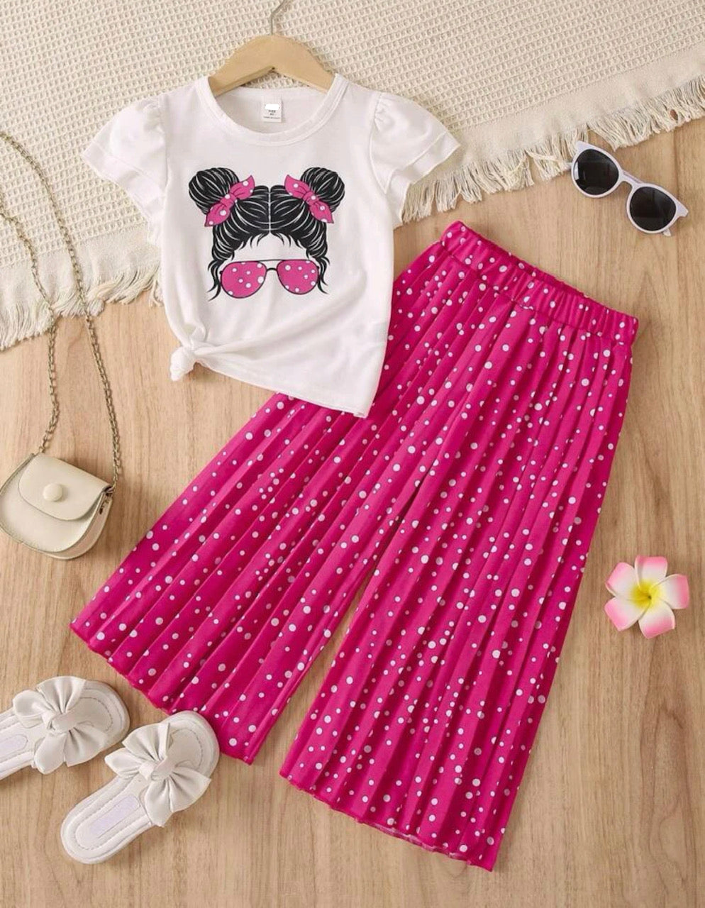 This stylish set is out of this world! Rock the galaxy with this cute and trendy look featuring an adorable graphic top, complete with a girl sporting space buns and hot pink spotted shades. Rock it with the included hot pink pleated wide leg pant with white splotches - your friends will wish they had your style-as well as your attitude!