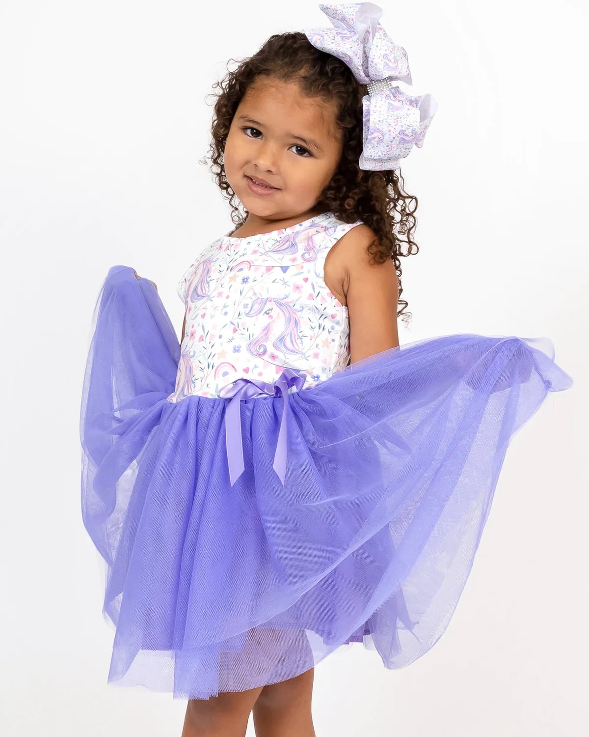 Put a sparkle in their step with a magical Lovely Unicorn Tulle Dress! The jewel neckline and sleeveless bodice features a charming unicorn and rainbow print, plus an adorable ribbon accent. The full purple tulle skirt is sure to capture the hearts of other little princesses! #OnceUponATime
