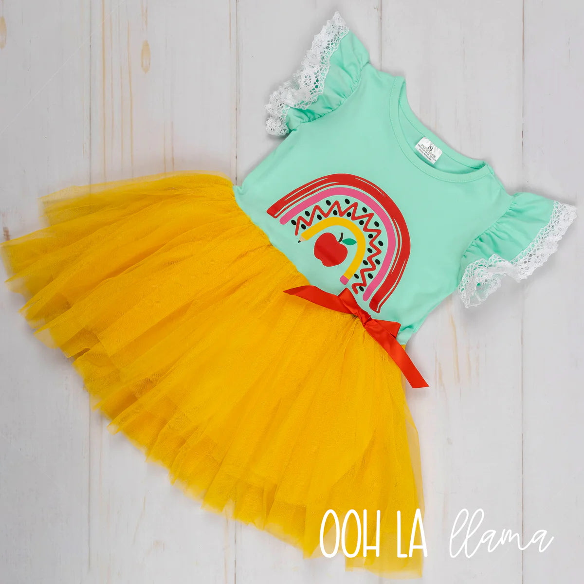 This Ray of Apples-Tulle Dress is a real show-stopper! Perfect for the classroom (or any occasion!), it features a school-inspired rainbow print design on the chest and a yellow tulle skirt topped off with a cute red bow. Plus, the ruffle flutter sleeve with lace trim is simply darling! Add a pop of whimsy to their wardrobe with this oh-so-adorable back-to-school dress!