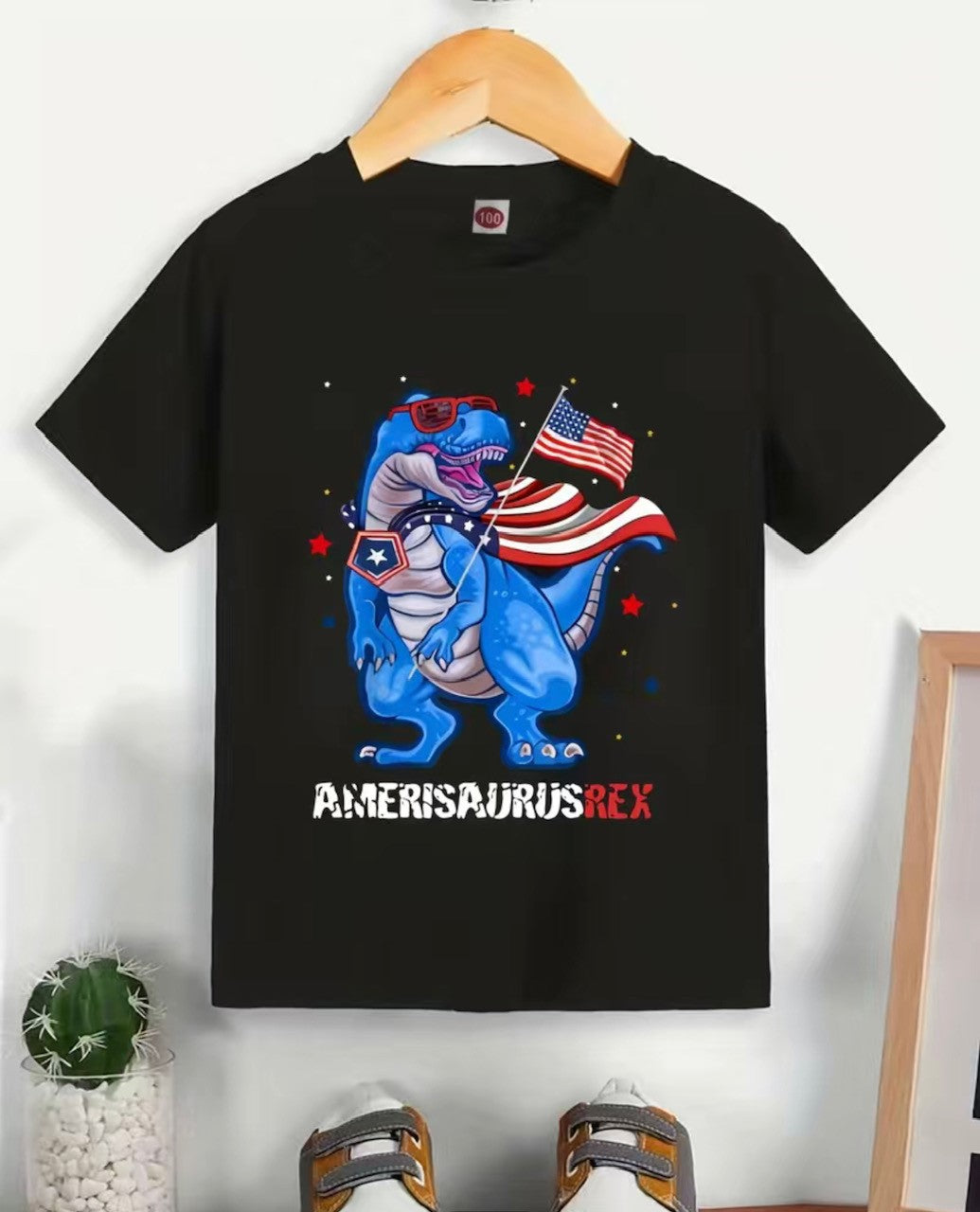 Introducing the Amerisaurus Rex T-Shirt! Step out and show off your American pride with this one-of-a-kind tee featuring a blue dinosaur all dressed up in the colors of the US flag! A perfect way to do patriotic style with flair, from Fourth of July to any day! 🇺🇸