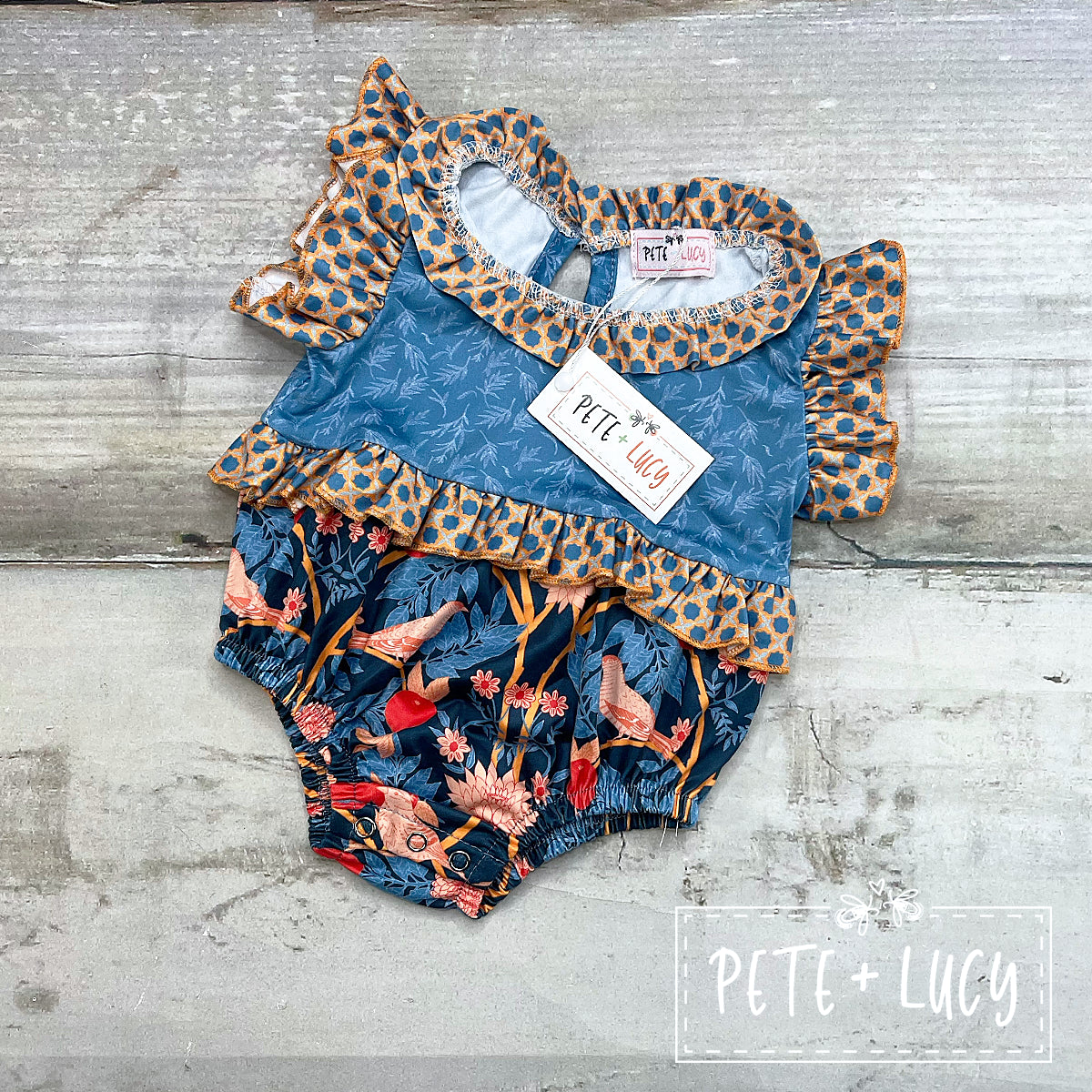 We love the use of the multi patterned fabrics on this adorable bubble romper! The ruffle on the tummy, sleeve and neckline help to add just the right amount of "sweet" to this precious romper. The use of the soft peach, blues, and a touch of red are the perfect combination of colors. A must for the spring/summer wardrobe!