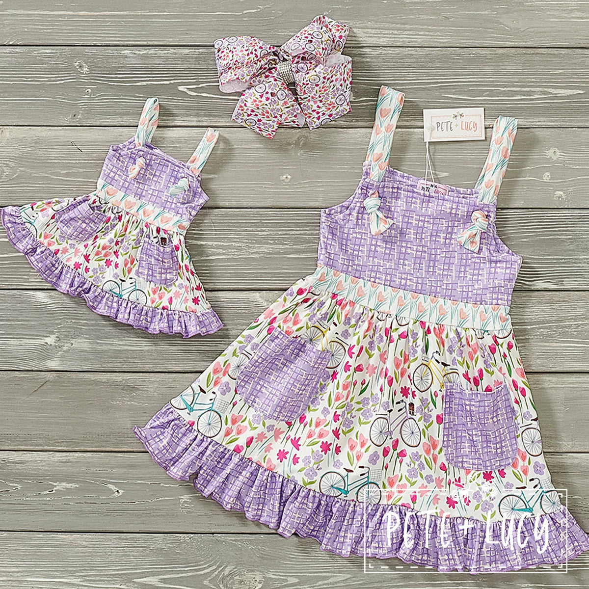 Loving this adorable Dress! The fabric combination of bicycles and tulips in contrast with the lavender check print is precious. We also love the ruffle hem and the knots that attach the straps to the front of the dress. We can't wait to see this beautiful dress on your little beauties this spring and summer!