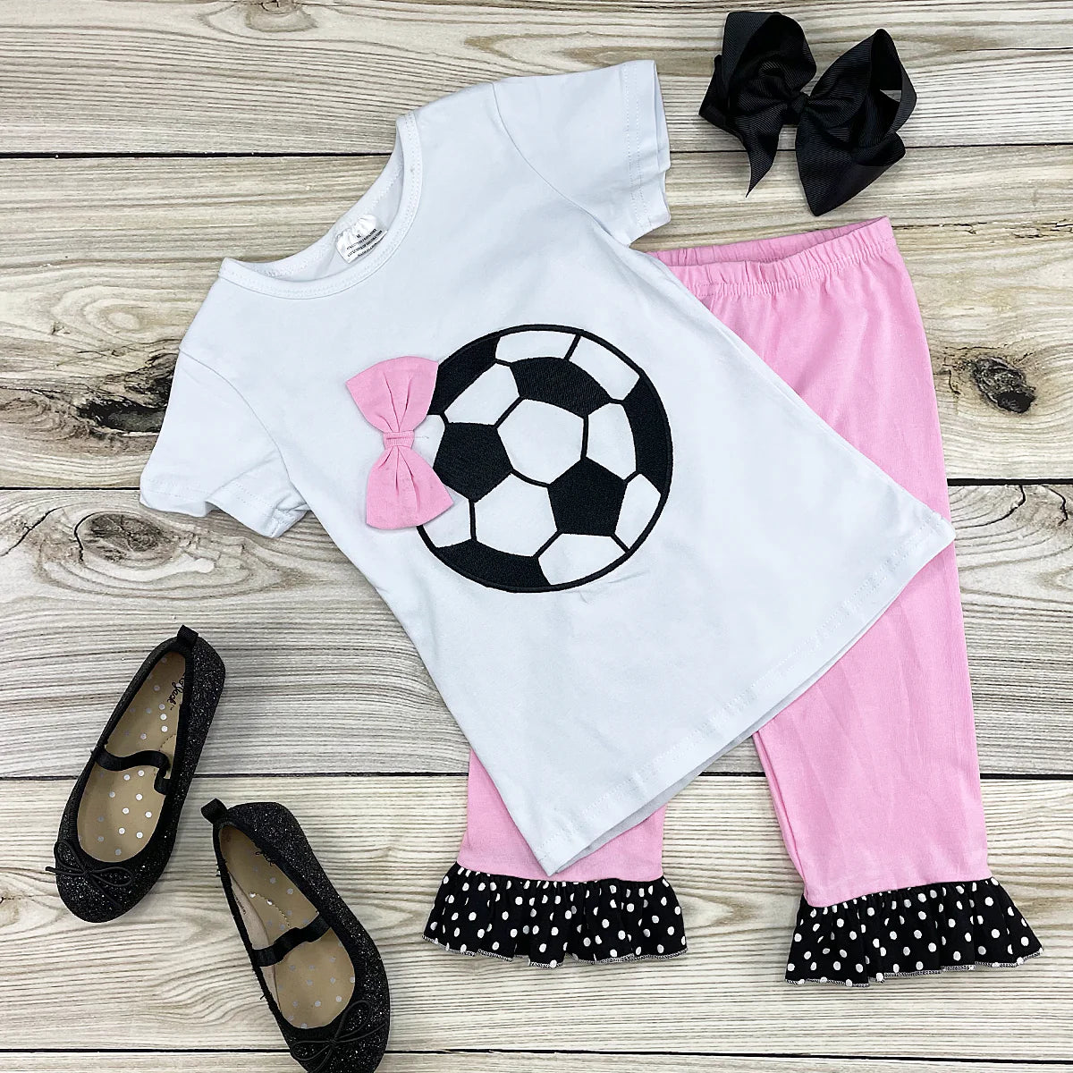 Forget the glass slippers this princess wears cleats!! We love how they added the adorable pink bow on the corner of the soccer ball on the shirt and the pink capri pant has an adorable black and white polka dot ruffle at the hem.This adorable 2-piece capri pant set is a must for your little princess!